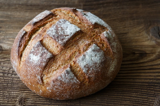 Ein frisch gebackenes rustikales Brot auf einem alten Holztisch