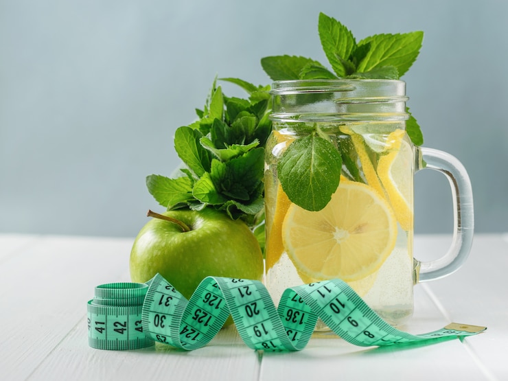 Ein frisch zubereitetes Getränk aus Zitrone, Minze und Apfel auf einem weißen Holztisch