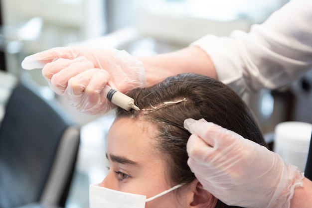 Ein Friseur wendet eine Behandlung an einem jugendlichen Kunden an, der eine Gesichtsmaske trägt