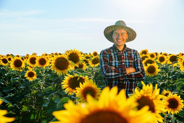 Ein fröhlicher Bauer steht mit verschränkten Armen zwischen den Sonnenblumen