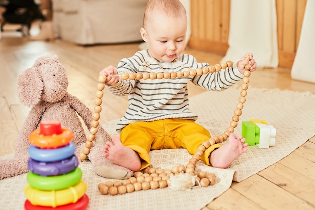 Foto ein fröhlicher, gesunder, hübscher kleiner junge, der auf dem holzboden des kinderzimmers kriecht