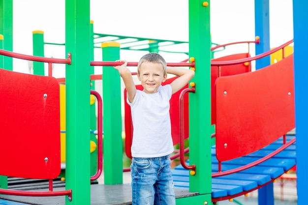 Ein fröhlicher Junge auf dem Spielplatz im Park der Sportanlage lacht und freut sich