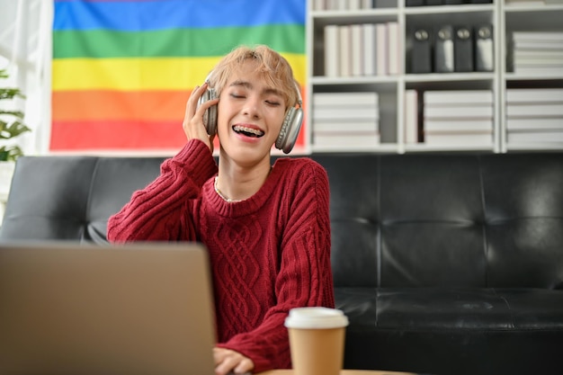 Ein fröhlicher junger asiatischer Schwuler genießt die Musik über seine Kopfhörer