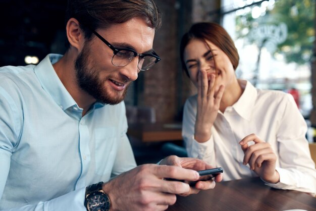 Ein fröhlicher Mann und eine fröhliche Frau sitzen in einem Café am Tisch und arbeiten an der Kommunikationstechnologie. Hochwertiges Foto