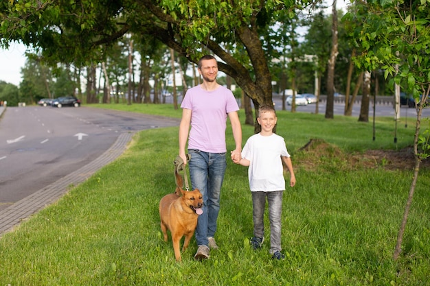 Ein fröhlicher Vater hält die Hand eines emotionalen Sohnes Ein Hund an der Leine