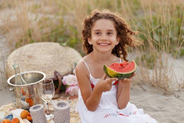 Ein fröhliches kleines Mädchen, das ein rotes Stück Wassermelone isst