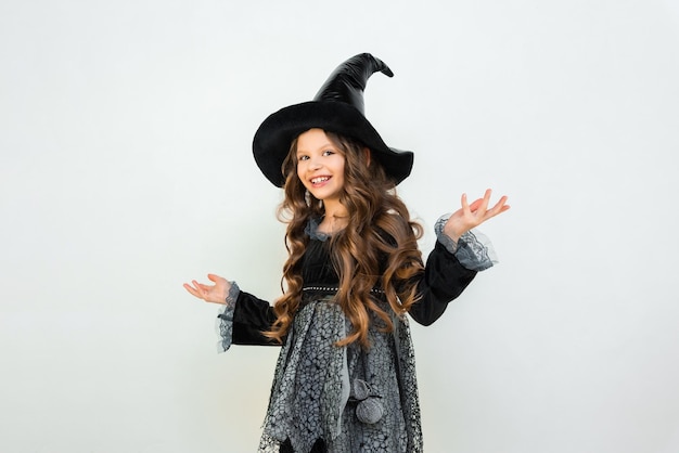 Ein fröhliches kleines Mädchen in einem Hexenkostüm auf weißem Hintergrund Schöne Zauberin-Kostüm-Halloween-Outfit