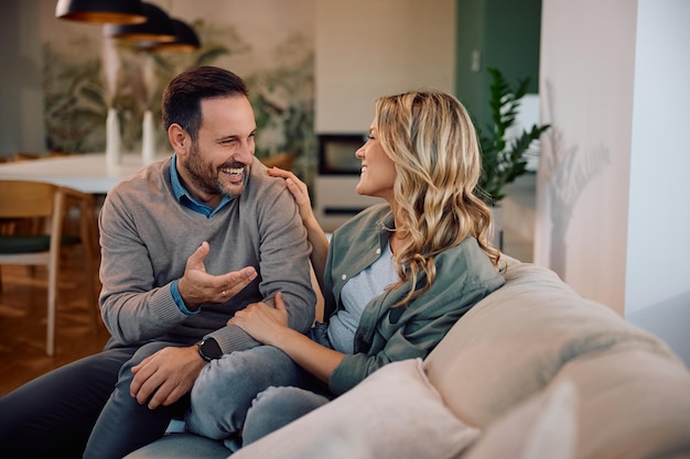 Ein fröhliches Paar unterhält sich, während es sich im Wohnzimmer entspannt