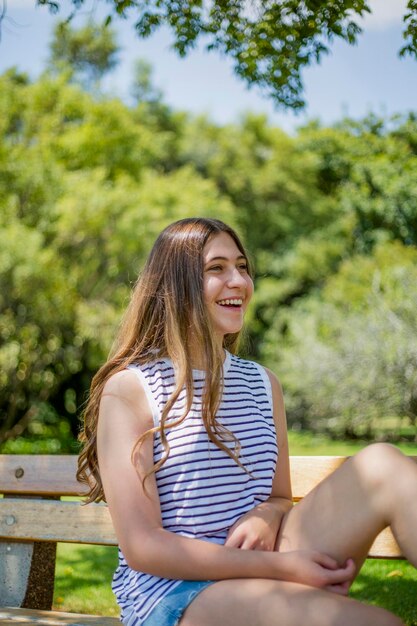 Ein fröhliches, süßes junges Mädchen, ein Teenager in einem gestreiften T-Shirt, verbringt Zeit im Park