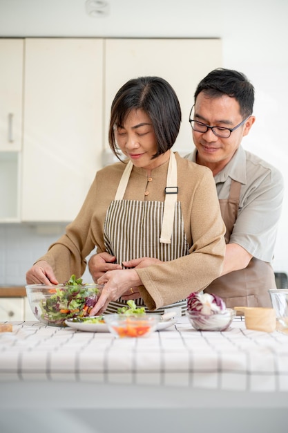 Ein fürsorglicher, romantischer asiatischer Ehemann umarmt seine Frau von hinten, während sie kocht