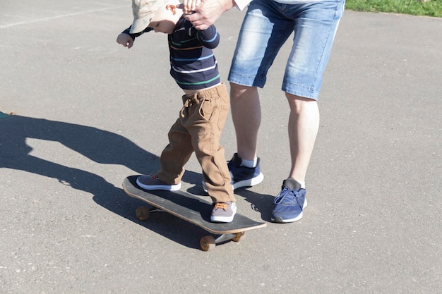 Ein fürsorglicher und liebevoller Vater bringt seinem dreijährigen Sohn das Skateboarden bei