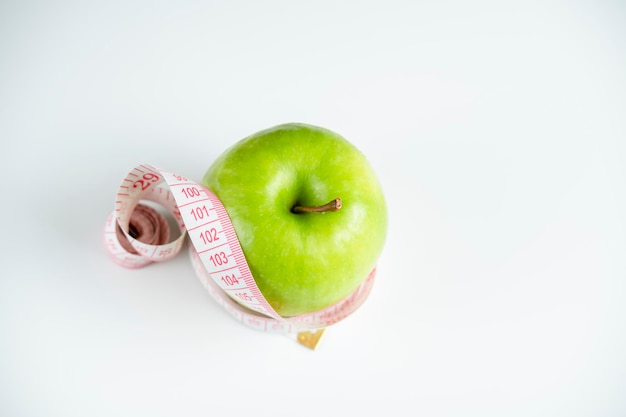 Ein ganzer grüner Apfel auf weißem Hintergrund mit einem Meter (Maßband)