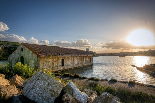 Ein Gebäude auf dem Wasser, hinter dem die Sonne untergeht