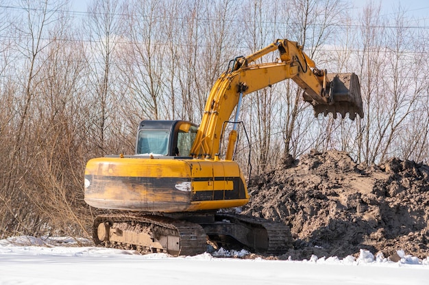 Foto ein gelber bagger steht auf einem erdhaufen.