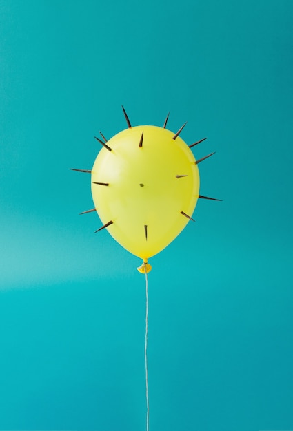 Ein gelber Ballon mit Stacheln schwebt vor einem hellblauen Hintergrund. Stärke-Konzept. Konzept der Selbstverteidigung. Minimale Komposition.