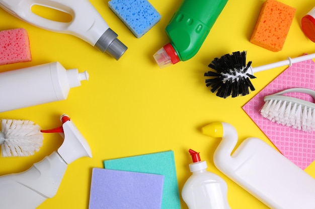 Ein gelber Hintergrund mit verschiedenen Reinigungsmitteln, darunter eine Flasche Reiniger, eine Bürste, eine Bürste, eine Bürste, eine rosa und blaue Box.