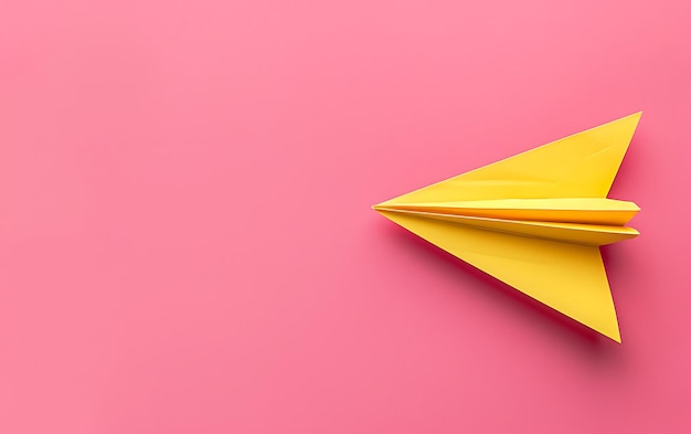 ein gelbes Papierflugzeug mit einer spitzen Spitze auf einem rosa Hintergrund