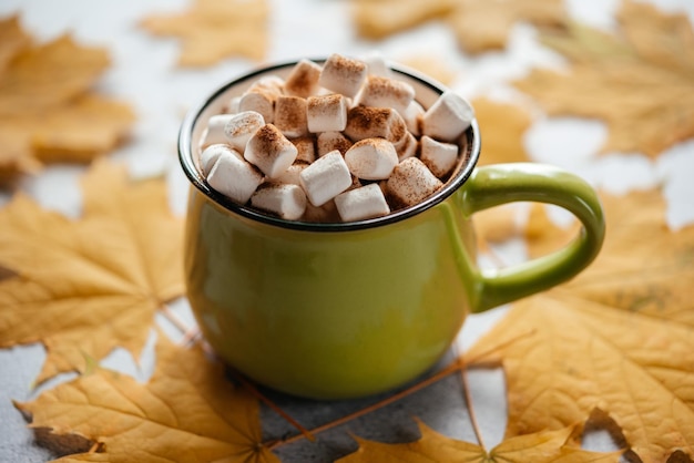 Ein gemütliches heißes Herbstgetränk mit Marshmallow und gelben Ahornblättern