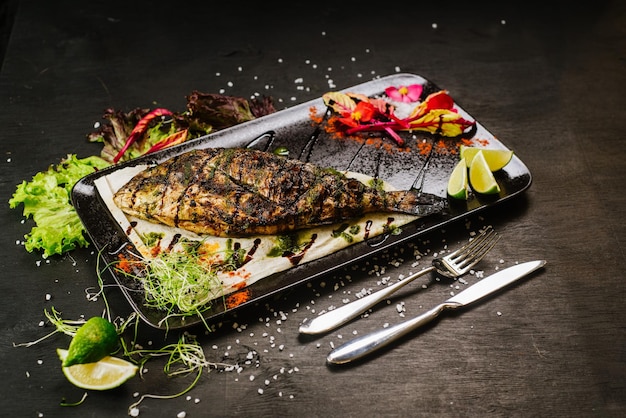 Ein Gericht mit gebratenem Fisch auf schwarzem Hintergrund