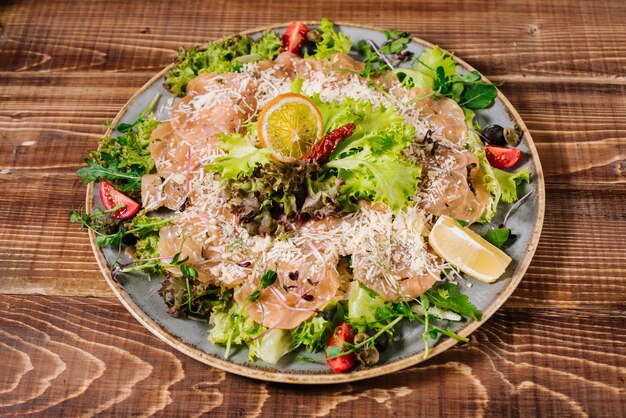 Foto ein gericht mit lachs, gemüse und kräutern auf holzhintergrund