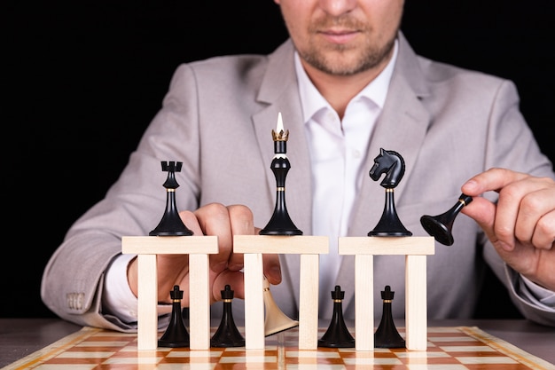 Ein Geschäftsmann baut eine Pyramide aus Schachfiguren und Holzklötzen