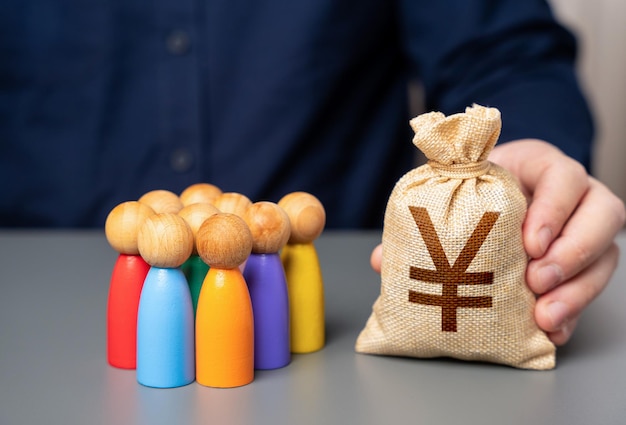 Ein Geschäftsmann hält einen Geldbeutel mit japanischen Yen in der Nähe einer Gruppe von Menschen Figuren Soziale Unterstützung Zuteilung von Haushaltsgeldern für Projekte Präferenzdarlehen für Unternehmer und Unternehmen
