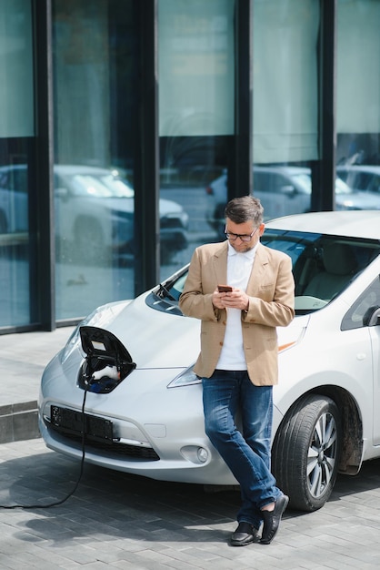 Ein Geschäftsmann lädt ein Elektroauto auf