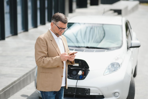 Ein Geschäftsmann lädt ein Elektroauto auf