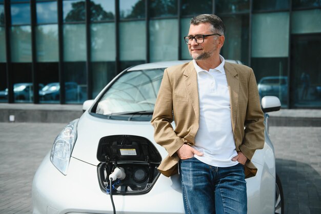 Ein Geschäftsmann lädt ein Elektroauto auf