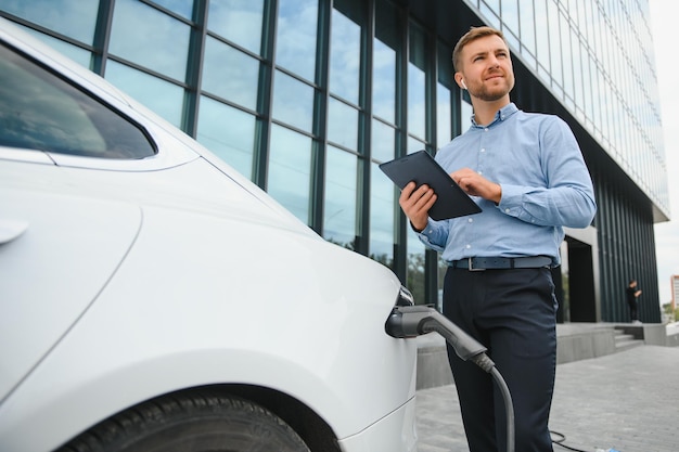 Ein Geschäftsmann lädt ein Elektroauto auf