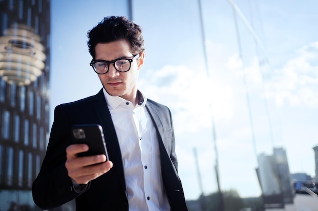 Ein geschäftsmann mit brille hält das telefon und geht zur arbeit im büro in einem geschäft