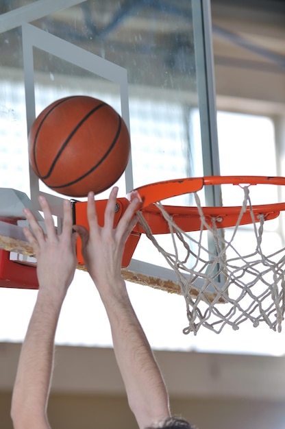 Ein gesunder junger Mann spielt Basketballspiel in der Turnhalle der Schule