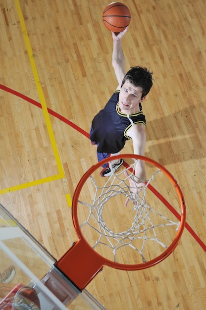 Ein gesunder junger Mann spielt Basketballspiel in der Turnhalle der Schule