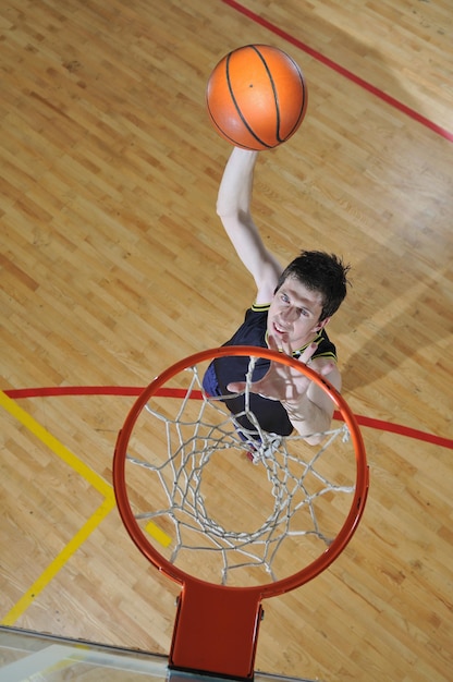 ein gesunder junger Mann spielt ein Basketballspiel im schulischen Fitnessstudio.