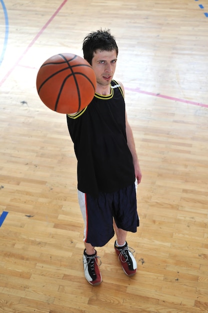 ein gesunder junger Mann spielt ein Basketballspiel im schulischen Fitnessstudio.