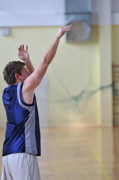 ein gesunder junger Mann spielt ein Basketballspiel im schulischen Fitnessstudio.