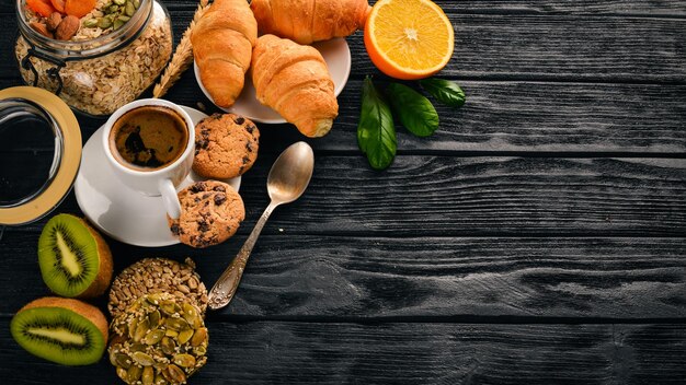 Ein gesundes Frühstück Orangensaft Kiwi Croissants Kekse Kaffee auf einer Holzoberfläche Draufsicht Freier Platz für Text
