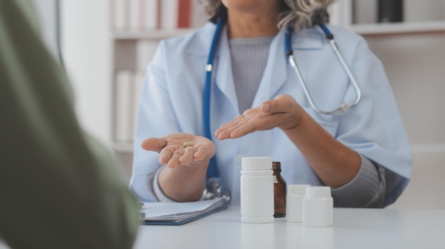 Ein Gesundheitsbesucher mit Tablet, der einer älteren Frau erklärt, wie man Pillen einnimmt