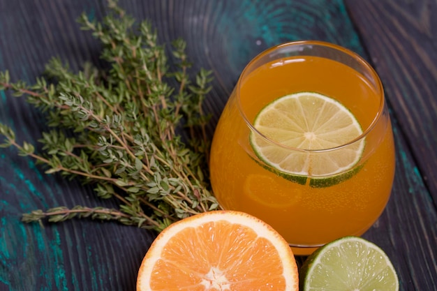 Foto ein glas alkohol, halbe limetten, orangen und thymian