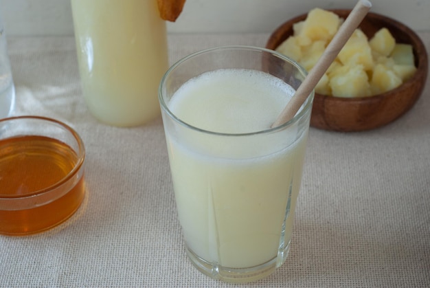 Ein Glas Ananassaft mit einem Holzlöffel darin.