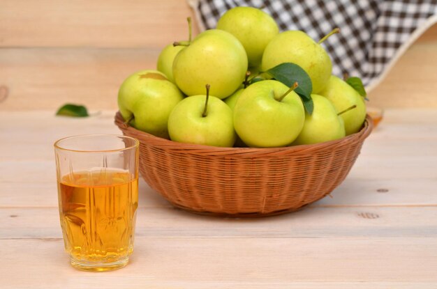 Ein Glas Apfelsaft und ein Korb mit Äpfeln auf dem Tisch