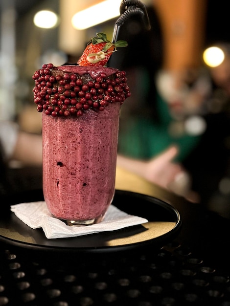 Ein Glas Beeren-Smoothie mit einer Erdbeere obendrauf