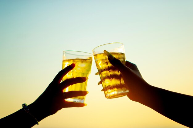 Ein Glas Bier anstoßen Nahaufnahme eines Glases kaltes Bier am Meer Die beiden strahlten glücklich