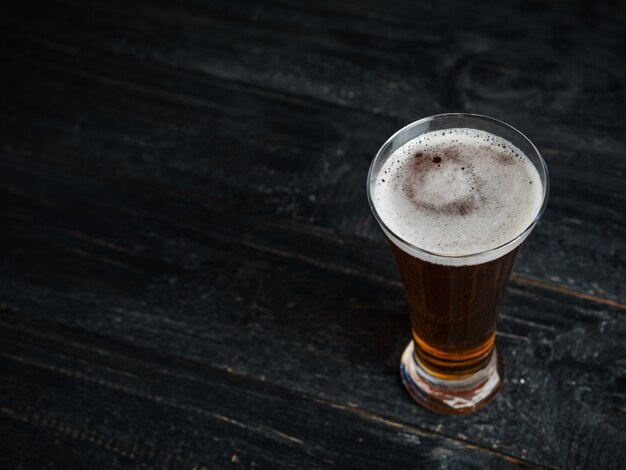 Ein Glas Bier auf einem dunklen Holztisch