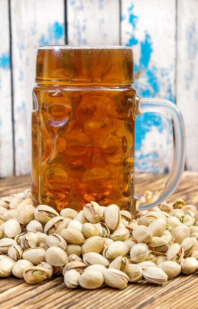 Ein Glas Bier mit Pistazien auf einem Holztisch