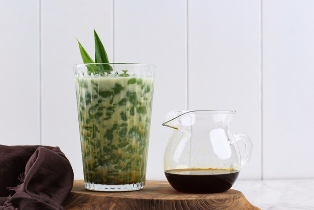 Ein Glas Cendol oder Dawet ist Indonesiens traditionelles Eisdessert aus Reismehl, Palmzucker, Kokosmilch und Pandablatt, das in Glas auf weißem Tisch serviert wird. Beliebt beim Fasten im Ramadan.