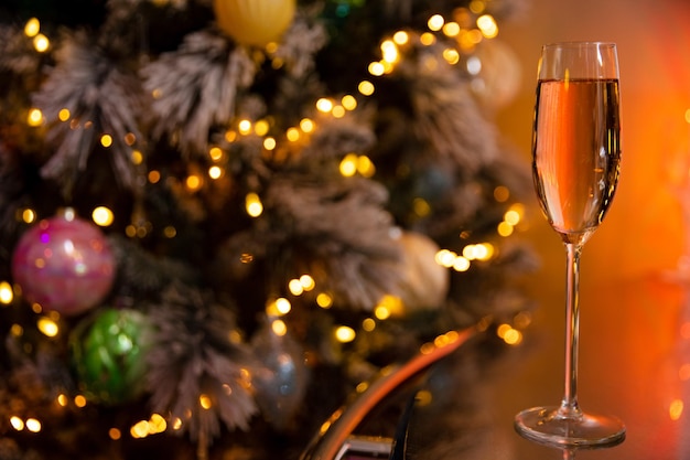 Ein Glas Champagner auf dem Hintergrund eines geschmückten Weihnachtsbaums