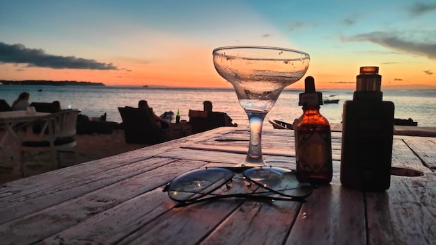 Foto ein glas champagner und eine flasche alkohol stehen auf einem tisch am strand.