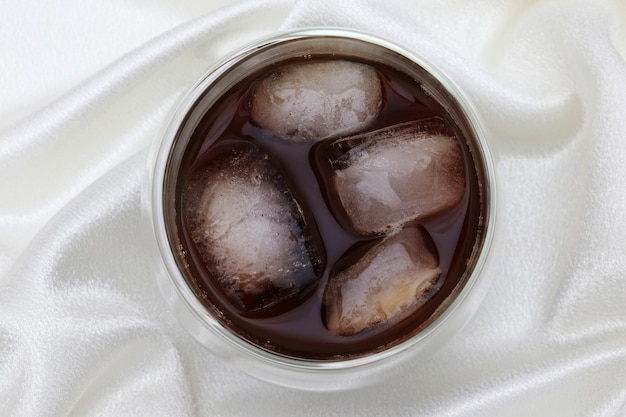 Ein Glas Cola mit Eiswürfeln darauf