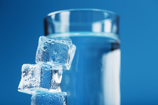 Ein Glas Eis und klares Wasser, Eiswürfel auf blauem Grund.